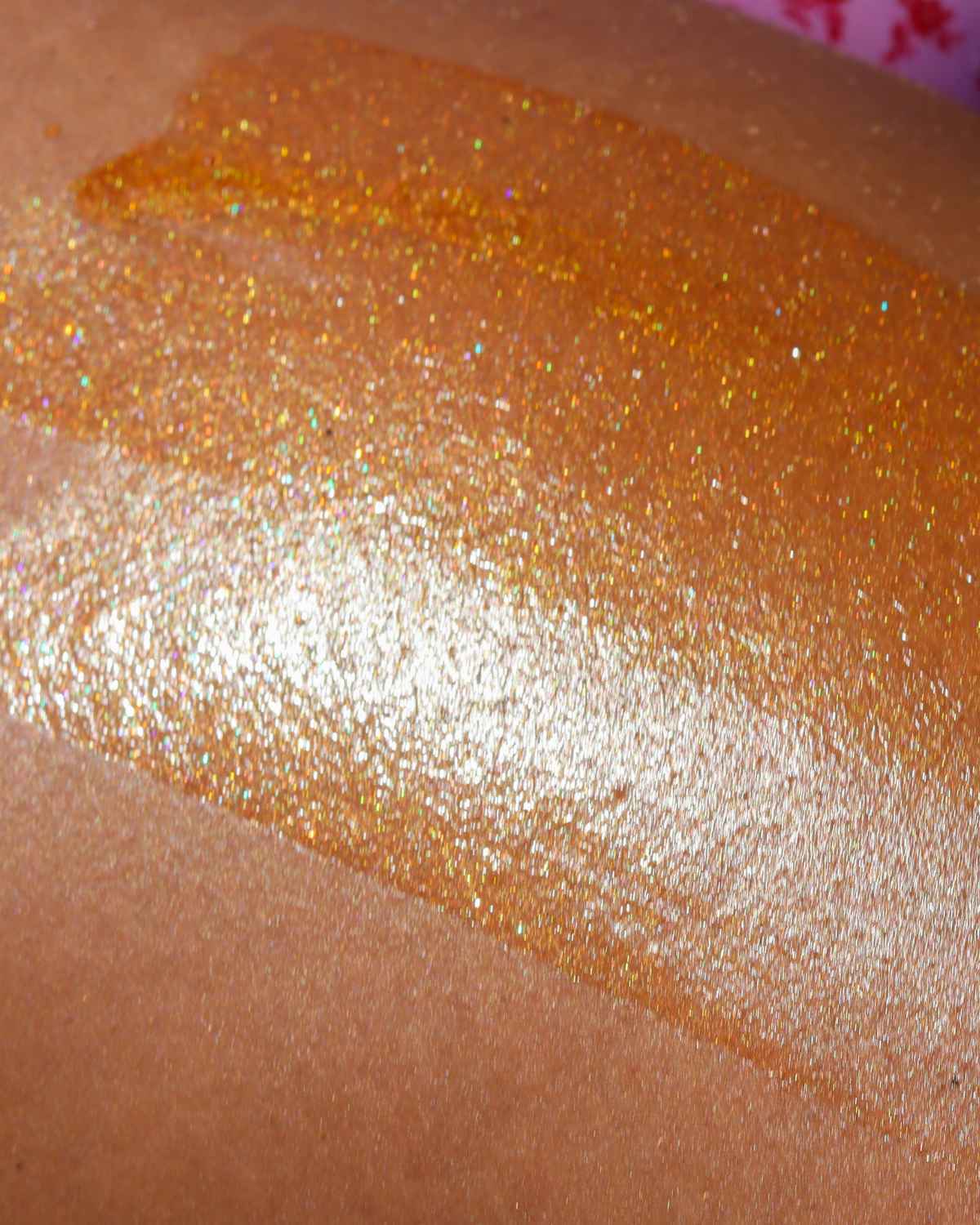 a texture shot of the attention seeker body shimmer oil on medium skin showing the glitter and bronzing effect