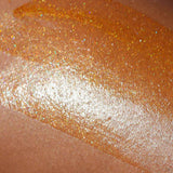 a texture shot of the attention seeker body shimmer oil on medium skin showing the glitter and bronzing effect