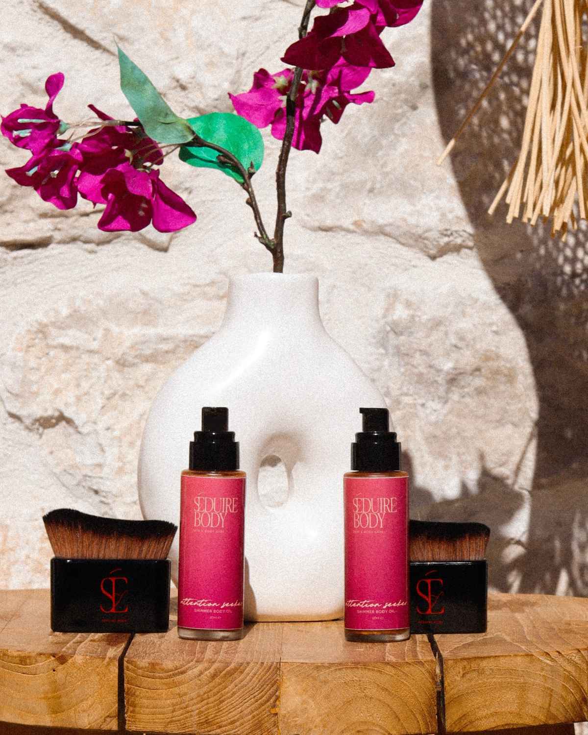 a photo of the attention seeker shimmer oil and body applicator brush in the sun with a vase behind