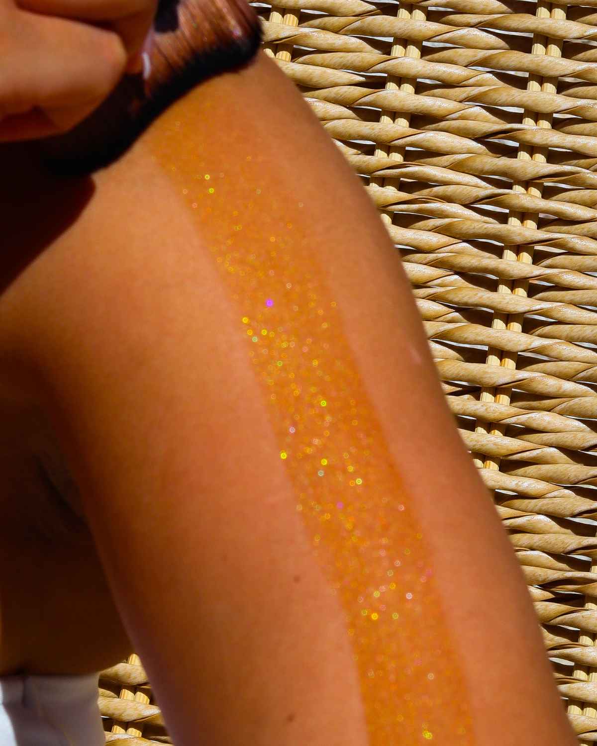 a close up photo of the attention seeker shimmer oil being applied to the skin showing the bronzing, iredescent glitter for body shimmer