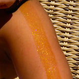 a close up photo of the attention seeker shimmer oil being applied to the skin showing the bronzing, iredescent glitter for body shimmer